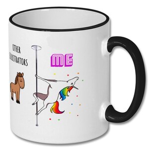 Op de afbeelding: Witte keramische koffiemok met een zwarte rand en handvat. De mok heeft een cartoon-einhorn op een paal dansen, met de tekst "OTHER ILLUSTRATORS" links en "ME" in roze letters rechts.