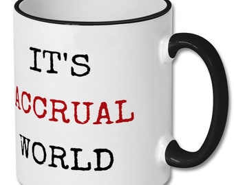 Może przedstawiać: Biały ceramiczny kubek do kawy z czarną obwódką i uchwytem. Kubek ma nadrukowany tekst "IT'S ACCRUAL WORLD" w kolorze czarnym i czerwonym.