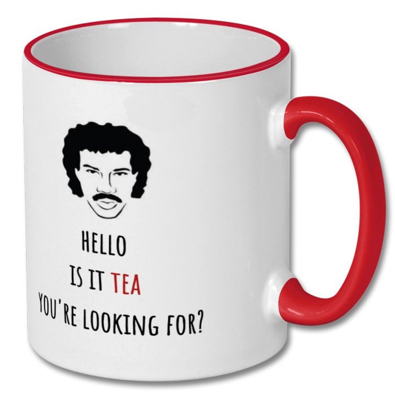 May include: White ceramic mug with a red rim and handle. The mug features a black and white illustration of a man with a moustache and the text "Hello is it tea you're looking for?"