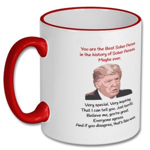 May include: White ceramic coffee mug with a red rim and handle. The mug features a humorous quote about sobriety with an image of a man. The text reads: "You are the Best Sober Person in the history of Sober Persons. Maybe ever. Very special. Very inspiring. That I can tell you. Just terrific. Believe me, you're great. Everyone agrees. And if you disagree, that's fake news."