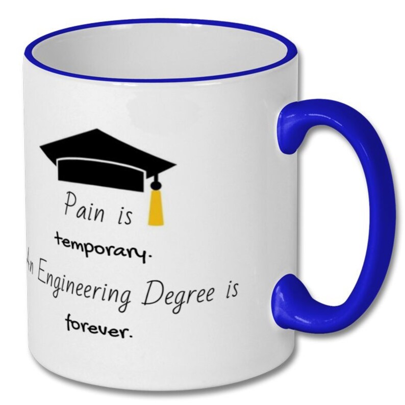 Op de afbeelding: Witte keramische koffiemok met een blauwe rand en handvat. De mok heeft een zwarte graduatiecap met een gele kwast en de tekst "Pijn is tijdelijk. Een ingenieursdiploma is voor altijd."