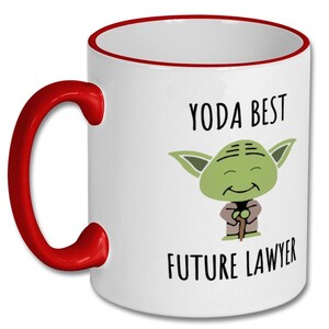 May include: White ceramic coffee mug with a red rim and handle. The mug features a cartoon image of Yoda from Star Wars holding a walking stick. The text "YODA BEST FUTURE LAWYER" is printed on the mug.