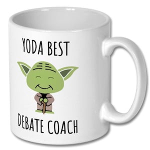 May include: White ceramic coffee mug featuring a green Yoda character illustration and the text "Yoda Best Debate Coach".