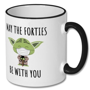 May include: White ceramic coffee mug with a black rim and handle. The mug features a cartoon image of Yoda wearing a face mask and the text "May the Forties Be With You".