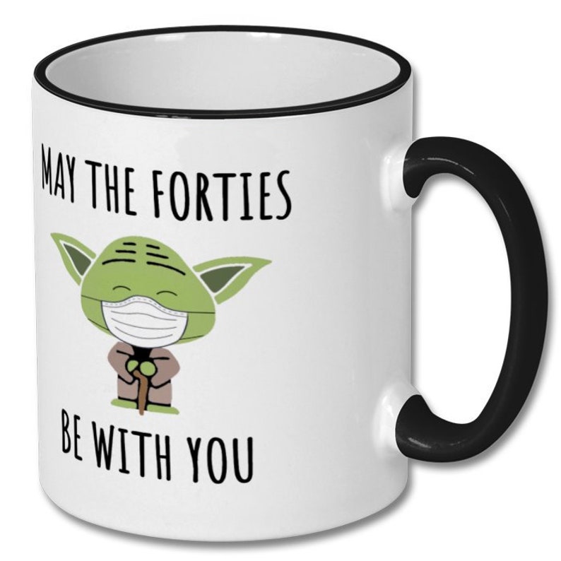 May include: White ceramic coffee mug with a black rim and handle. The mug features a cartoon image of Yoda wearing a face mask and the text "May the Forties Be With You".