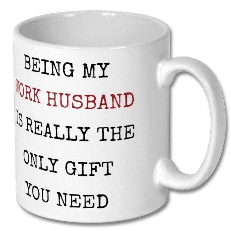 May include: White ceramic mug with a curved handle. The mug features the text "BEING MY WORK HUSBAND IS REALLY THE ONLY GIFT YOU NEED" in black and red lettering. A gift for a coworker.
