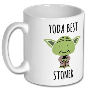 May include: White ceramic mug with a green Yoda character holding a walking stick. The text "YODA BEST STONER" is printed on the mug.