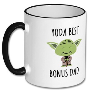 May include: White ceramic mug with a black rim and handle. The mug has a cartoon image of Yoda with the text "Yoda Best Bonus Dad".