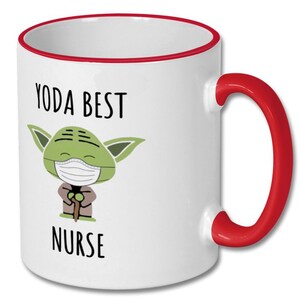 K&ouml;nnte beinhalten: Wei&szlig;e Keramiktasse mit rotem Rand und Henkel. Die Tasse zeigt ein Cartoon-Bild von Yoda, der eine Gesichtsmaske tr&auml;gt und einen Stock h&auml;lt. Der Text "YODA BEST NURSE" ist auf die Tasse gedruckt.