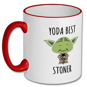 May include: White ceramic mug with a red rim and handle. The mug features a cartoon image of Yoda from Star Wars with the text "Yoda Best Stoner".