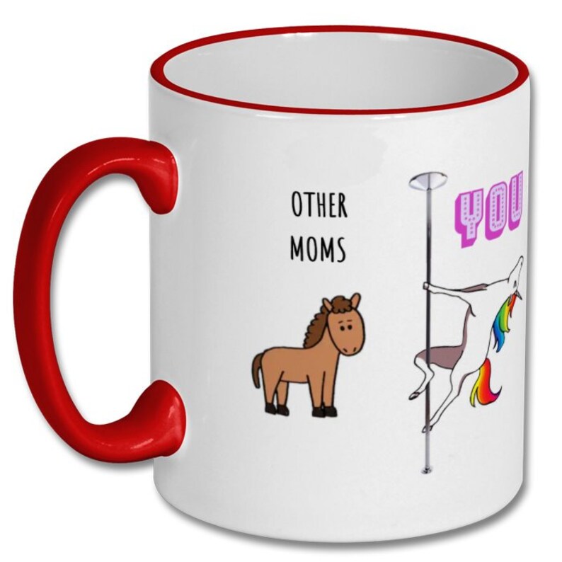 May include: White ceramic coffee mug with a red rim and handle. The mug has a cartoon illustration of a unicorn on a pole dancing, with the text "YOU" in pink letters. The text "OTHER MOMS" is printed above the unicorn, and a brown horse is illustrated to the left of the text.