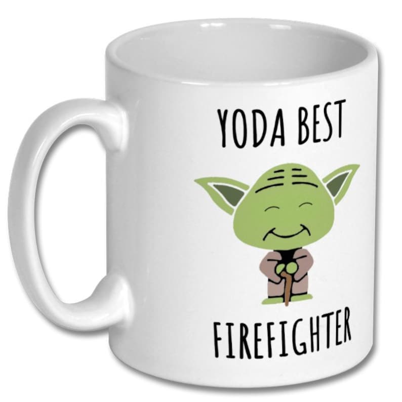 May include: White ceramic coffee mug with a green cartoon Yoda character holding a stick. The text "YODA BEST FIREFIGHTER" is printed on the mug.