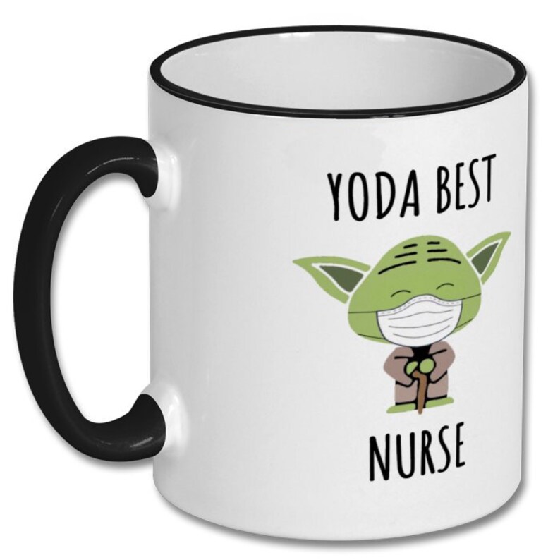 K&ouml;nnte beinhalten: Wei&szlig;e Keramiktasse mit schwarzem Rand und Henkel. Die Tasse zeigt ein Cartoon-Bild von Yoda, der eine Gesichtsmaske tr&auml;gt und einen Gehstock h&auml;lt. Der Text "YODA BEST NURSE" ist auf die Tasse gedruckt.