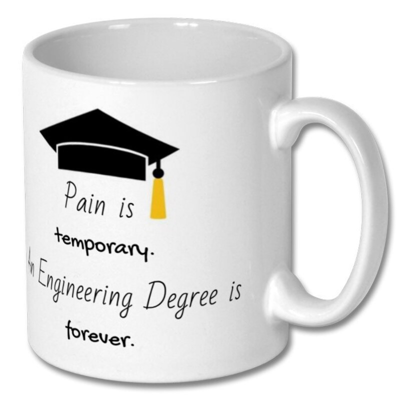 Op de afbeelding: Een witte keramische koffiemok met een zwarte afstudeerhoed en de tekst "Pijn is tijdelijk. Een ingenieursdiploma is voor altijd."