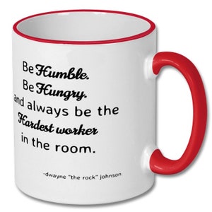 May include: White ceramic coffee mug with a red rim and handle. The mug features a motivational quote by Dwayne "The Rock" Johnson: "Be Humble. Be Hungry. And always be the Hardest worker in the room."