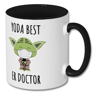 Może przedstawiać: Biały kubek ceramiczny z czarnym rantem i uchwytem. Kubek przedstawia kresk&oacute;wkową postać Yody w maseczce i napis "YODA BEST ER DOCTOR".