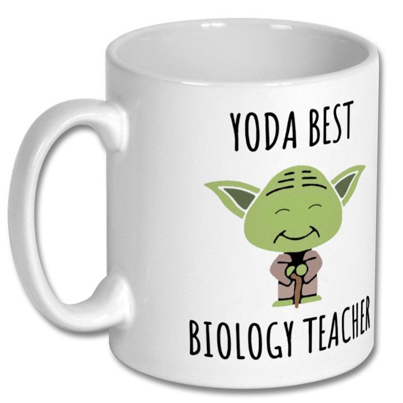 May include: White ceramic coffee mug with a green cartoon character of Yoda from Star Wars. The text "Yoda Best Biology Teacher" is printed on the mug.