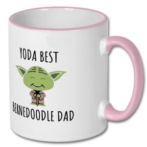 May include: White ceramic mug with a pink rim and handle. The mug features a cartoon image of Yoda with the text "Yoda Best Bernedoodle Dad".