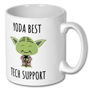 May include: White ceramic coffee mug with a green cartoon Yoda character holding a walking stick. The text "YODA BEST TECH SUPPORT" is printed on the mug.