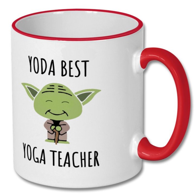 May include: White ceramic coffee mug with a red rim and handle. The mug features a cartoon image of Yoda from Star Wars with the text "Yoda Best Yoga Teacher".
