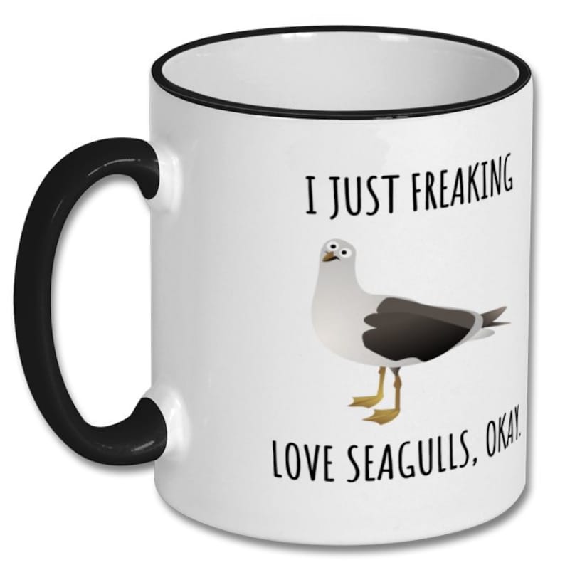 May include: White ceramic coffee mug with a black rim and handle. The mug features a cartoon seagull and the text "I just freaking love seagulls, okay!"
