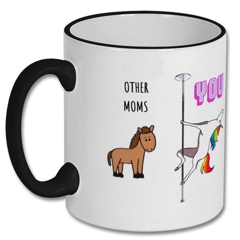 May include: White coffee mug with a black rim and handle. The mug has a cartoon image of a horse and a unicorn on a pole. The text "Other Moms" and "You" are printed on the mug.
