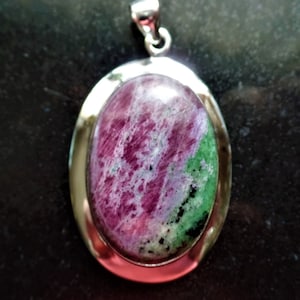 May include: A silver pendant featuring a green and pink oval gemstone. The gemstone has a swirling pattern of pink and green.