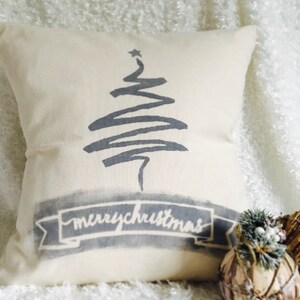 May include: A white throw pillow with a gray stylized Christmas tree and a banner that reads "merrychristmas".
