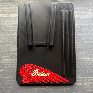 Puede incluir: Soporte rectangular negro con soportes elevados y la palabra "Indian" en una fuente estilizada. El logotipo presenta un perfil rojo de un jefe nativo americano con un dise&ntilde;o de ala roja.