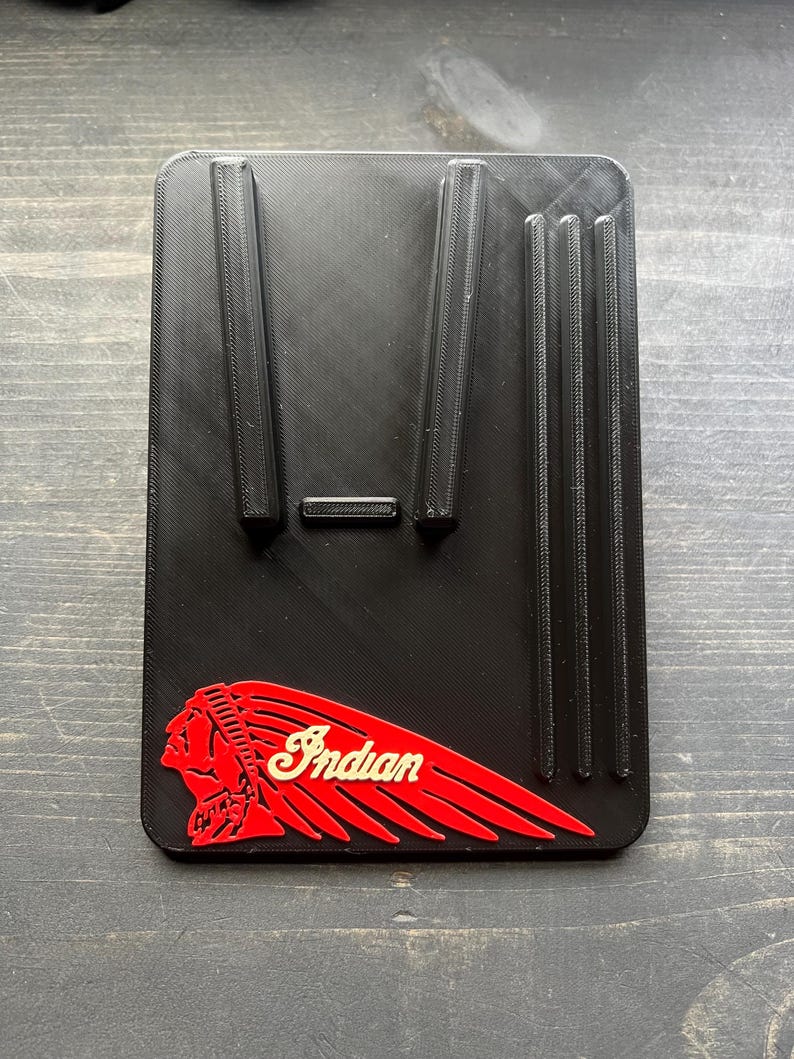 Puede incluir: Soporte rectangular negro con soportes elevados y la palabra "Indian" en una fuente estilizada. El logotipo presenta un perfil rojo de un jefe nativo americano con un dise&ntilde;o de ala roja.