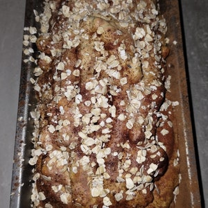 May include: A loaf of bread topped with oats and cinnamon in a loaf pan.