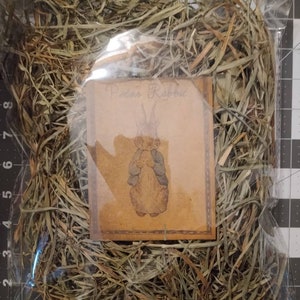 May include: A clear plastic bag filled with dried grass, labeled "Peter Rabbit".