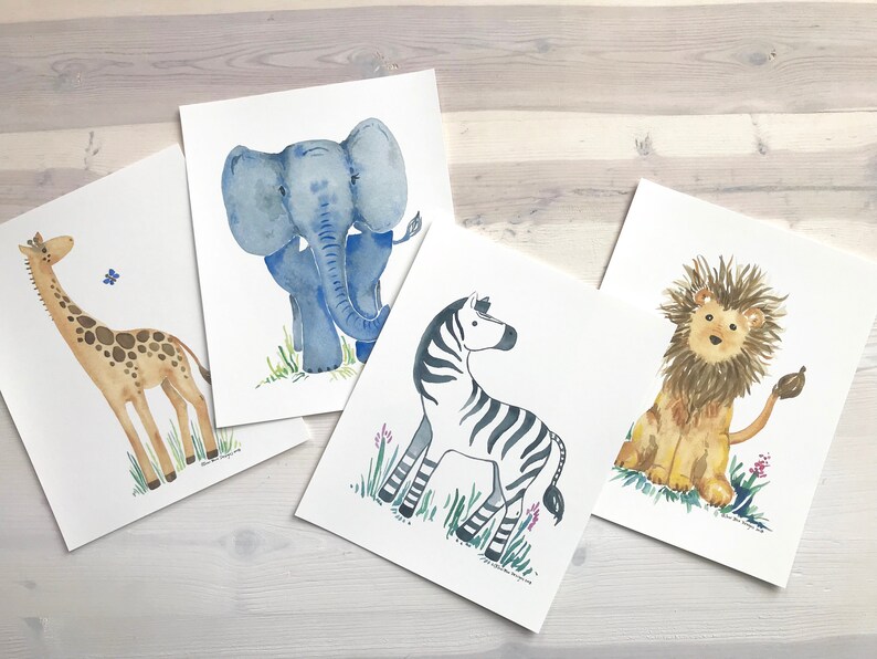 Pu&ograve; includere: Quattro acquerelli di animali africani su carta bianca. Gli animali sono una giraffa, un elefante, una zebra e un leone. La giraffa &egrave; marrone con un collo lungo e macchie. L'elefante &egrave; blu con grandi orecchie. La zebra &egrave; nera e bianca con strisce. Il leone &egrave; marrone con una criniera.