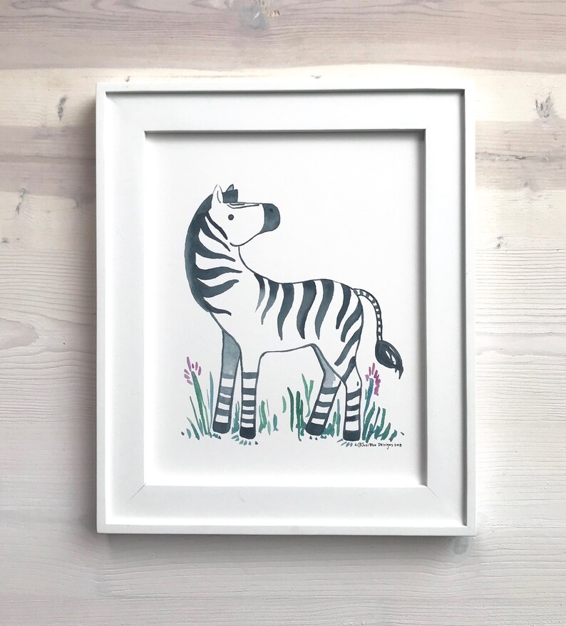 Pu&ograve; includere: Un dipinto ad acquerello incorniciato di una zebra in piedi in un campo di erba verde con fiori viola. La zebra &egrave; nera e bianca con un corpo grigio. Il dipinto &egrave; firmato "Olivia Rose Designs 2019".
