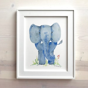 Pu&ograve; includere: Un dipinto ad acquerello di un elefante blu in piedi su un prato verde. L'elefante ha una lunga proboscide e grandi orecchie. Il dipinto &egrave; incorniciato in una cornice bianca.