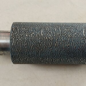 May include: A silver metal roller with a textured surface. The roller has a black and white pattern.