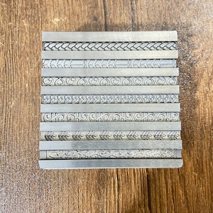 May include: A metal plate with eight different decorative patterns engraved on it. The patterns are all intricate and detailed, and they would be perfect for adding a touch of elegance to any project.