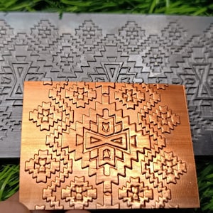 Könnte beinhalten: Zwei Metallplatten mit einem geometrischen Muster. Die obere Platte ist silberfarben und die untere Platte ist kupferfarben.