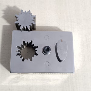May include: A silver metal plate with three cutouts: a star shape, a circle, and an oval. The star shape is also a separate piece that can be removed.