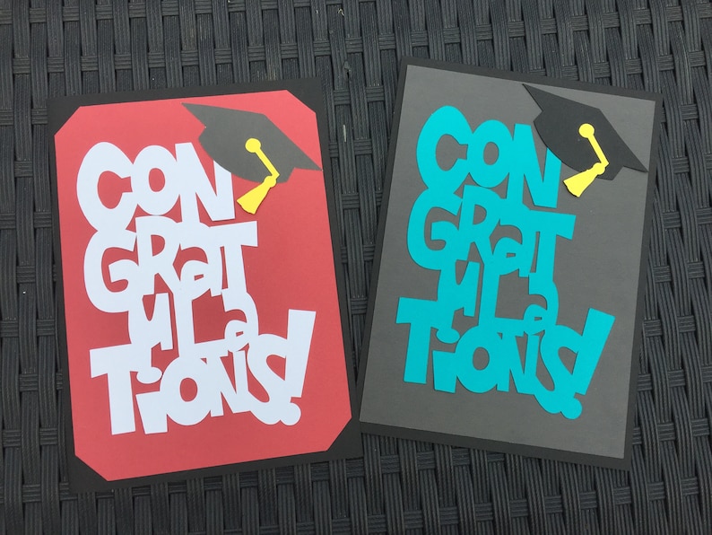 May include: Two graduation cards with the words "Congratulations" in white and turquoise letters on red and gray backgrounds. Each card has a black graduation cap with a yellow tassel.