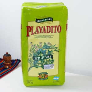 May include: A bright green packet of Yerba Mate tea, labelled "PLAYADITO" with Spanish text. The packet features a botanical illustration of herbs and the text "HIERBAS". The net weight is 500g.