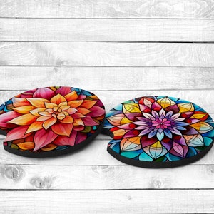 May include: Two colorful round coasters with floral designs. One coaster features a large pink and orange flower with yellow accents. The other coaster features a blue, purple, and yellow flower with a mandala-like design.