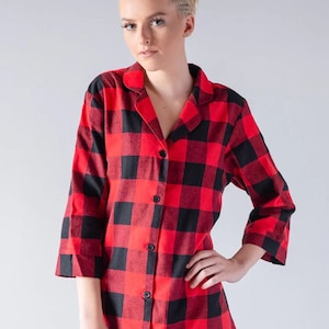 May include: Red and black plaid flannel shirt dress with a button-up front and long sleeves.