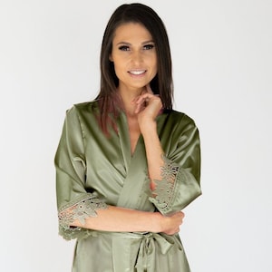May include: A sage green satin robe with lace trim on the sleeves and hem. The robe has a tie belt and a V-neck.