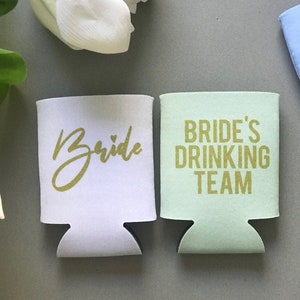 May include: Two white and green foam can coolers with gold lettering. One cooler says "Bride" and the other says "Bride's Drinking Team".