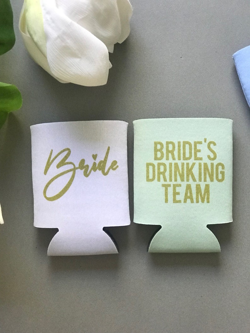 May include: Two white and green foam can coolers with gold lettering. One cooler says "Bride" and the other says "Bride's Drinking Team".