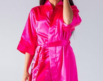 May include: A bright pink satin robe with a self-tie belt. The robe has a classic kimono style with long sleeves and a relaxed fit.