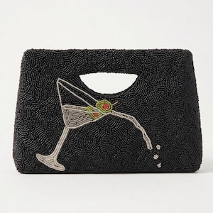 K&ouml;nnte beinhalten: Schwarze, perlenbesetzte Clutch mit Henkel. Die Clutch zeigt ein Martini-Glas-Design mit Oliven-Akzenten. Das Martini-Glas besteht aus silbernen und gr&uuml;nen Perlen. Die Clutch hat eine rechteckige Form.