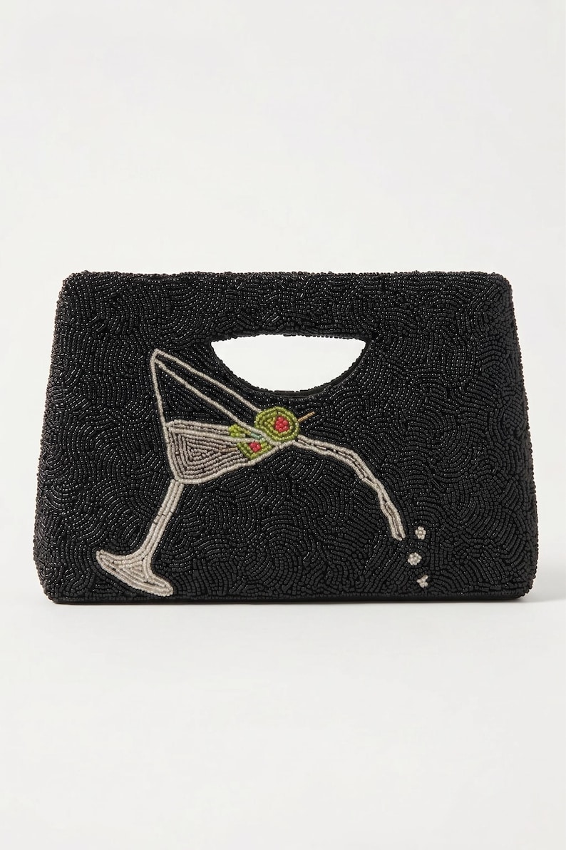 K&ouml;nnte beinhalten: Schwarze, perlenbesetzte Clutch mit Henkel. Die Clutch zeigt ein Martini-Glas-Design mit Oliven-Akzenten. Das Martini-Glas besteht aus silbernen und gr&uuml;nen Perlen. Die Clutch hat eine rechteckige Form.