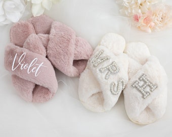 Può includere: Un paio di pantofole pelose, una rosa con il nome "Violet" ricamato su di essa, e l'altra bianca con "Mrs" e "Mr" scritti in strass.